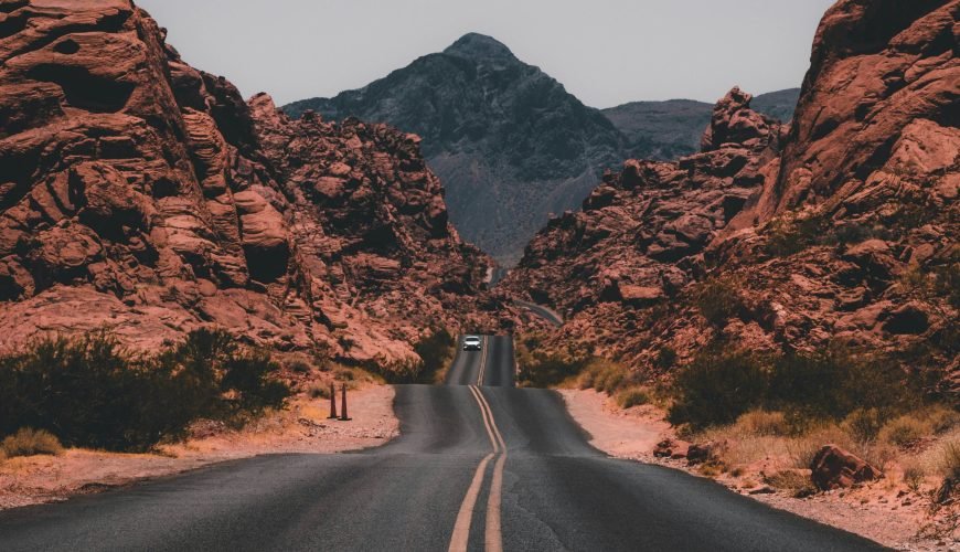 black concrete road surrounded by brown rocks